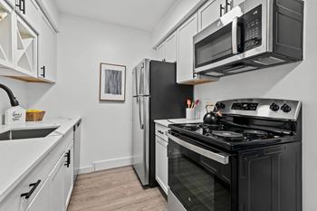 A modern kitchen with a black stove and white cabinets.